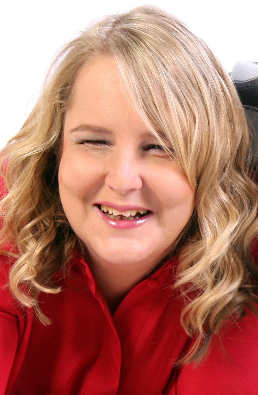 A photograph of Stacey. She has long blonde hair and is wearing a cherry red shirt.