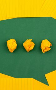 three crumpled yellow papers on green surface surrounded by yellow lined papers